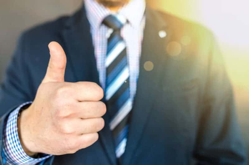 Person in suit and tie offering a thumbs up