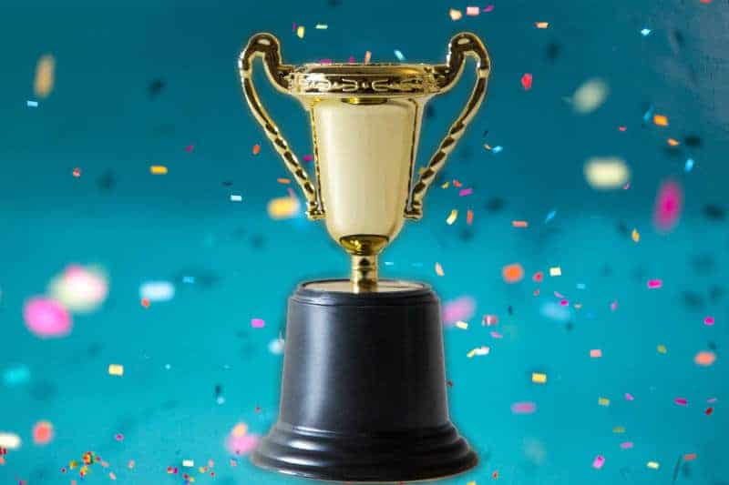 Gold double-handled trophy on a blue confetti background