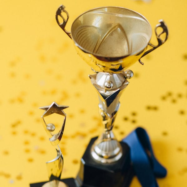 Two golden trophies on a yellow background